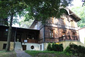 una vecchia casa in legno con un albero di fronte di Willa Widok - Apartament Naleczow a Nałęczów