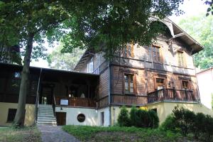 una vieja casa de madera con un árbol delante en Willa Widok - Apartament Naleczow, en Nałęczów