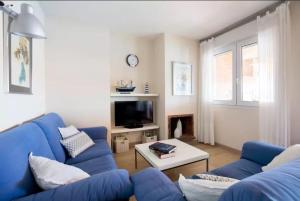 sala de estar con sofá azul y TV en Terrassa de Mar, en L'Escala