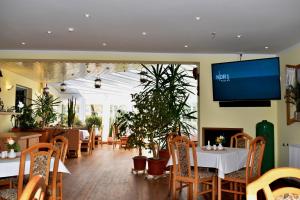 ein Restaurant mit Tischen und Stühlen und einem Flachbild-TV in der Unterkunft Hotel Seeadler in Zempin