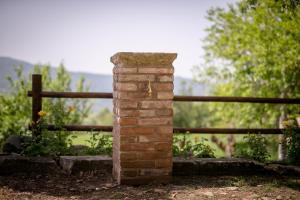 un montante di mattoni di fronte a una recinzione di legno di Borgo Al Teto Il Gelso a Castiglion Fiorentino