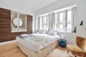 a white bedroom with a large bed and a chair at Rue du Louvre - Luxury apartment in Paris