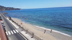 een strand waar mensen naast het water staan bij Loft Panorama di Naxos in Giardini Naxos