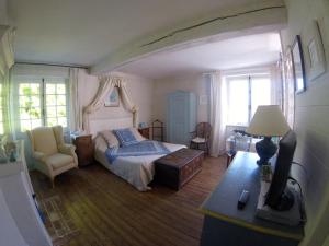 1 dormitorio con 1 cama, 1 silla y ventanas en Clos de la Rose, en Saint-Cyr-sur-Morin