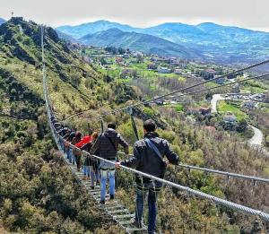 a group of people walking on a suspension bridge on a mountain at La Cantina del Convento in Potenza