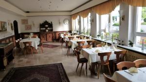 un restaurante con mesas y sillas blancas y ventanas en Hotel Bürgerhof en Homburg