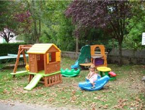 ein Kind spielt auf einem Spielplatz mit Spielgeräten in der Unterkunft Camping La Clé des Champs in Saint-Nectaire