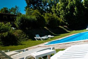 uma piscina com espreguiçadeiras e uma mesa ao lado em Viviendas Rurales Traldega em Turieno