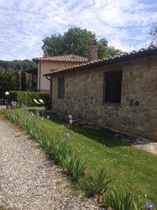 a stone house with a yard with purple flowers at Borgo del Molinello in Sant'Albino