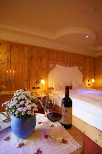 a room with two glasses of wine and a bed at Hotel Bellavista in Canazei