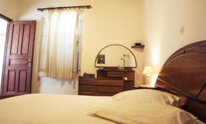 Un dormitorio con una cama, una cómoda y un espejo. en Seasidehouse, en Hydra