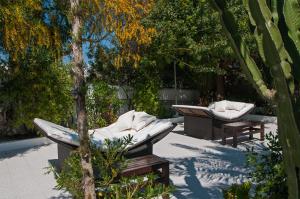 a patio with two lounge chairs and a tree at Secret Oasis Ibiza-Only Adults in San Antonio Bay