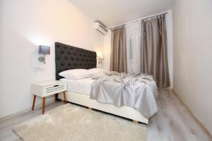 a white bedroom with a bed and a window at Apartments Maruna Self check-in in Zadar