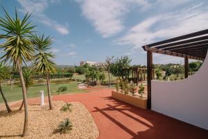 a courtyard with palm trees and a building at Quinta dos Poetas Nature Hotel & Apartments in Olhão