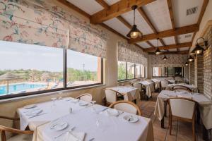 a restaurant with white tables and chairs and a large window at Quinta dos Poetas Nature Hotel & Apartments in Olhão