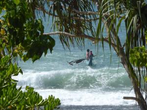 two people standing in the ocean with a surfboard at Villa Sunrise in Tangalle