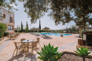 a patio with tables and chairs next to a pool at Quinta dos Poetas Nature Hotel & Apartments in Olhão