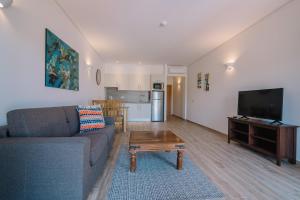 a living room with a couch and a tv and a table at Quinta dos Poetas Nature Hotel & Apartments in Olhão