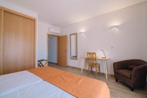 a bedroom with a bed and a chair and a table at Quinta dos Poetas Nature Hotel & Apartments in Olhão