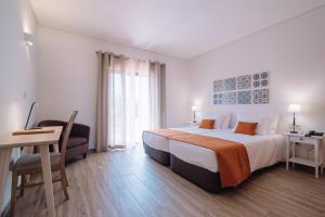 a hotel room with a bed and a desk and a bed sidx sidx sidx sidx at Quinta dos Poetas Nature Hotel & Apartments in Olhão