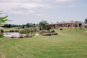 a park with a pond and a bridge in the background at Quinta dos Poetas Nature Hotel & Apartments in Olhão