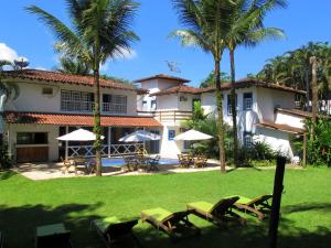 a house with palm trees and chairs in the yard at Pousada Villa Del Rey POSSUIMOS GERADOR in Paraty