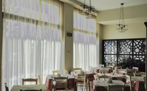 a dining room with white tables and chairs and windows at Artemis in Tolo