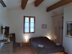 a bedroom with a bed and a desk and a window at A CASA DI L'ALIVU in Patrimonio