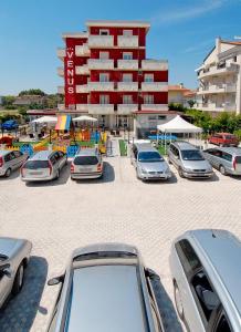 a parking lot with cars parked in front of a building at Hotel Venus in Riccione