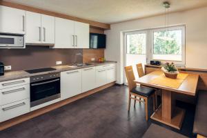 a kitchen with white cabinets and a wooden table at Appart Collina in Pfunds