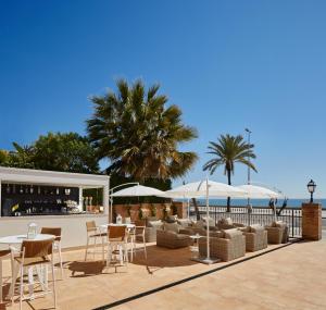 un patio con tavoli, sedie e ombrelloni di Hotel Casa Vilella 4* Sup a Sitges