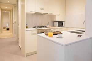 a kitchen with white cabinets and a island with a bowl of fruit on it at Bravissimo Cort Reial-1A in Girona