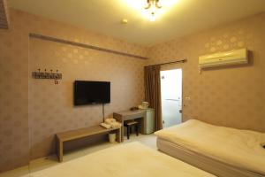 ein Schlafzimmer mit einem Bett und einem Flachbildfernseher in der Unterkunft Hilarity B&B in Hualien