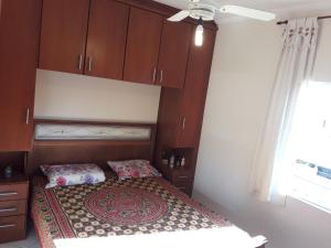 a bedroom with a bed with wooden cabinets at Apto no Ed. Alexandra I in Guarujá