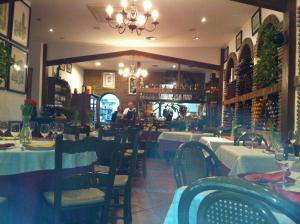 a restaurant with tables and chairs and a person in the background at Hostal El Puerto in Caleta De Velez