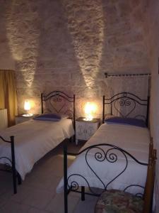 2 camas en una habitación con 2 lámparas en Trulli Sarmenzanello, en Noci