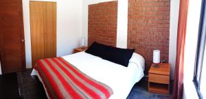 a bedroom with a bed and a brick wall at Departamentos Incahuasi in Bahia Inglesa