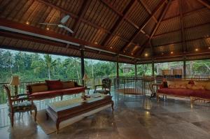 a living room with furniture and a view of the forest at Natya Resort Ubud in Ubud