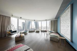 JEN Beijing by Shangri-La في بكين: غرفة معيشة بها كنب وكراسي ونوافذ كبيرة