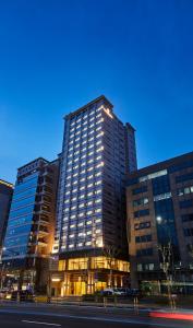 a tall building with lights in front of a street at The Recenz Dongdaemun Hotel in Seoul