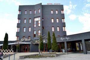 un edificio gris con un árbol delante de él en Hotel Plaza en Mladá Boleslav