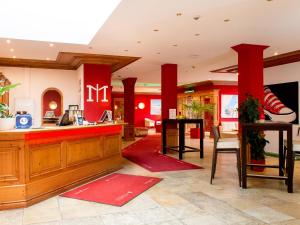 a restaurant lobby with red pillars and a counter at DORMERO Hotel Plauen in Plauen