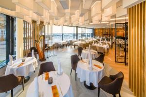 restauracja z białymi stołami i krzesłami oraz oknami w obiekcie Hotel New Skanpol w Kołobrzegu
