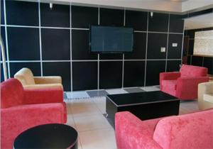 a living room with red chairs and a flat screen tv at Travelodge by Wyndham Absecon Atlantic City in Absecon +9 photos