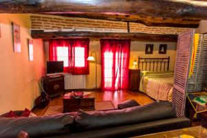 a bedroom with red curtains and a bed and a couch at El castanar in San Esteban de la Sierra