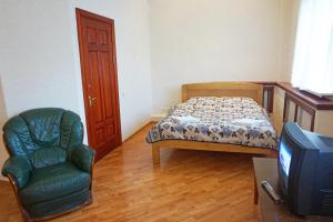 a bedroom with a bed and a chair and a tv at Apartament Erfolg 8 in Daugavpils
