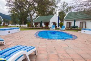 una piscina con 2 sillas y una casa en Swallows Nest Country Cottages en Stormsrivier