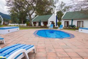 a swimming pool with two chairs and a house at Swallows Nest Country Cottages in Stormsrivier