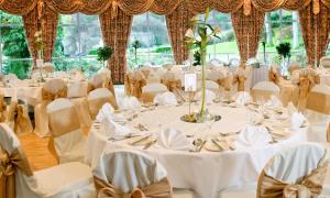 una sala per banchetti nuziali con tavoli e sedie bianchi di The Glendalough Hotel a Laragh