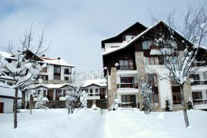 a building covered in snow with trees in front of it at PM Services Semiramida Apartments in Borovets